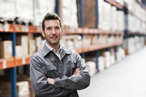 Man with arms crossed standing in an inventory warehouse